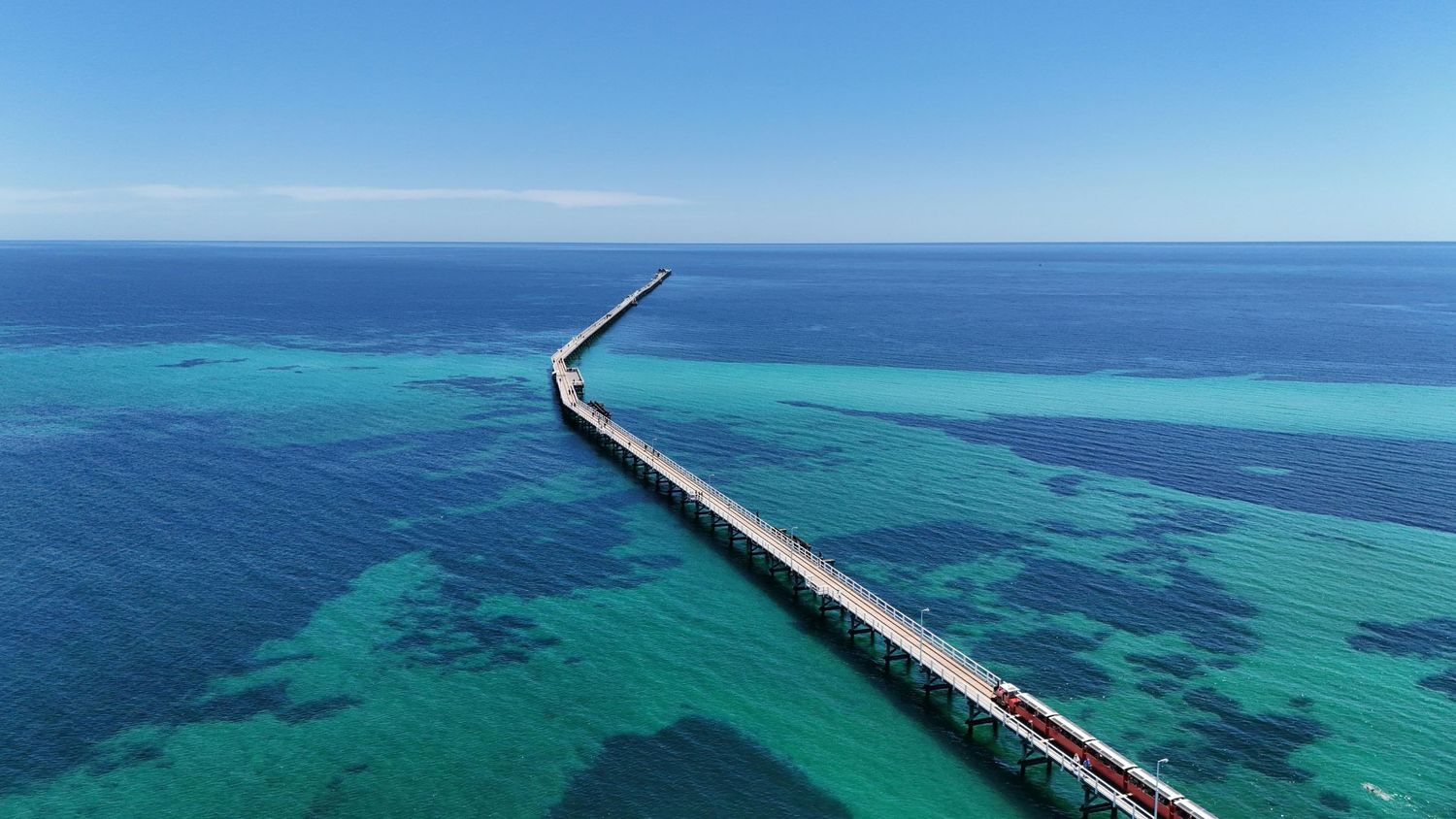 Aerial view of a long bridge stretching over turquoise waters under a clear blue sky in the Florida Keys.