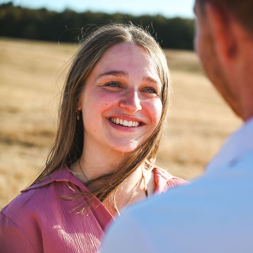 Gros plan visage souriant d'une femme dans un champ de blé, épaule d'un homme visible