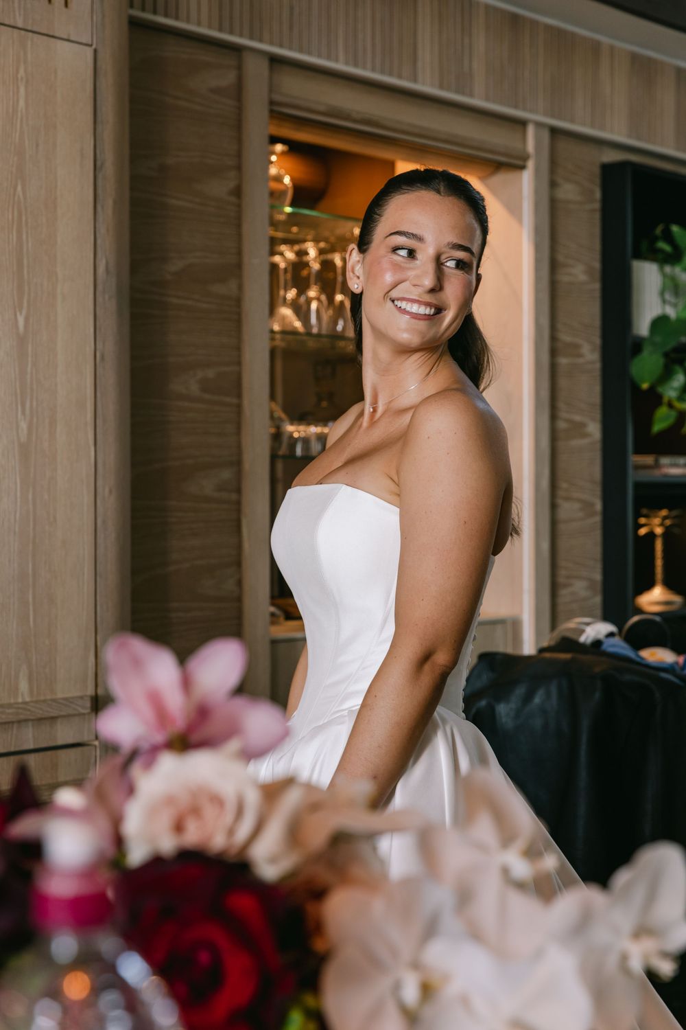 Smiling bride during her wedding reception, glowing in a timeless strapless gown.