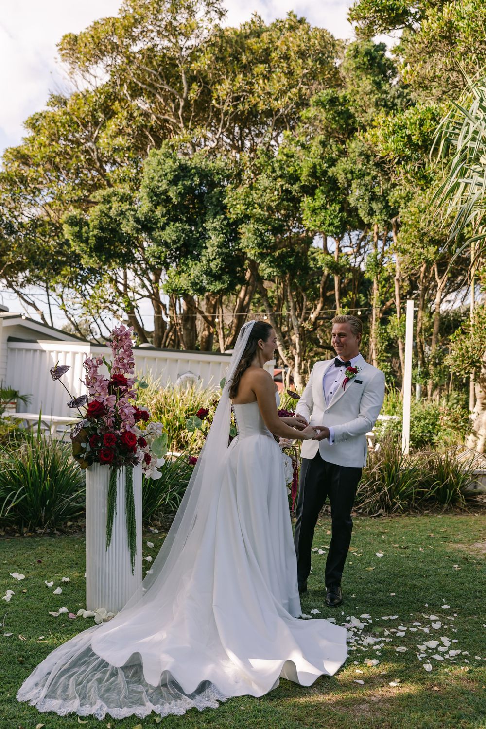 Newlyweds celebrating beneath a floral wedding arbour after exchanging vows in Byron Bay.