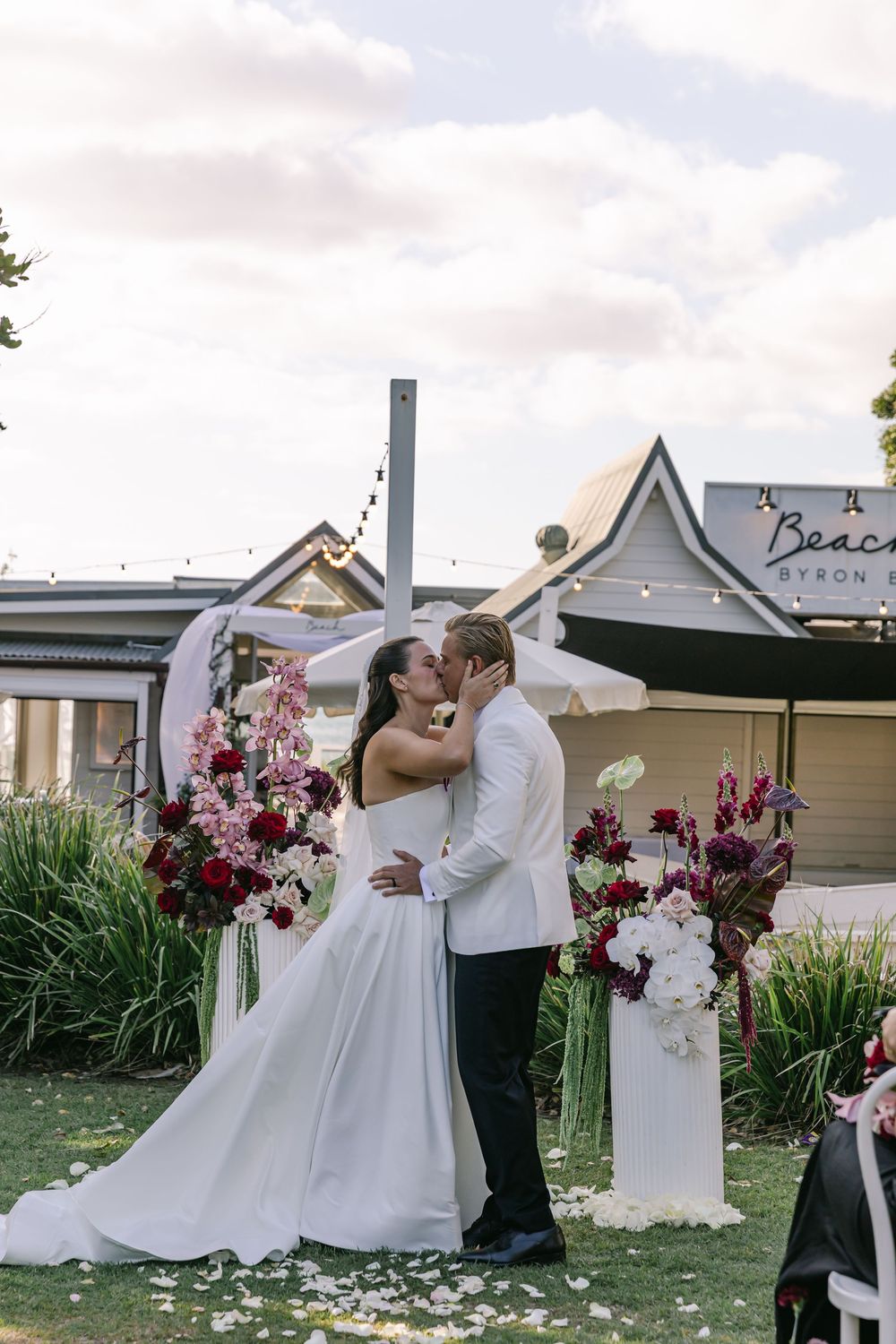 Bride and groom sharing a kiss during their elegant outdoor wedding ceremony in Byron Bay.