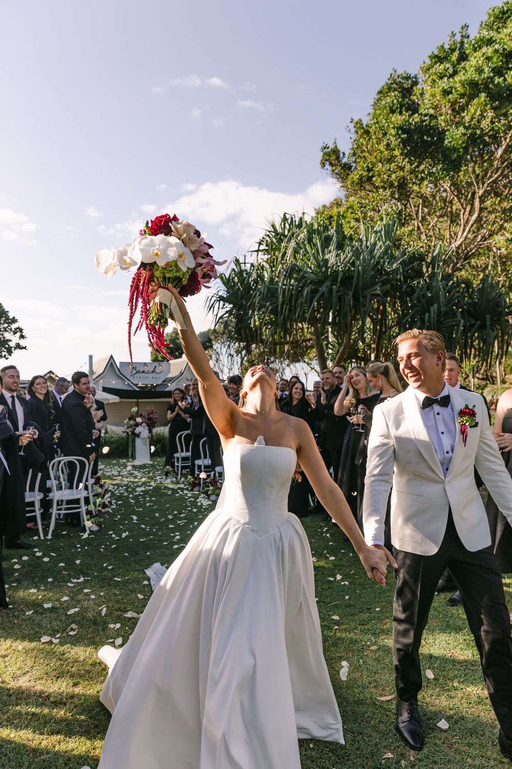 Bride and groom celebrating with family and friends after their joyful Byron Bay wedding ceremony.