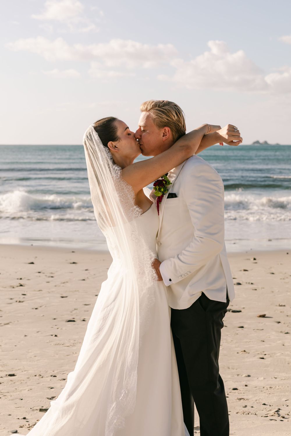 Newlyweds sharing an embrace on the beach following their Byron Bay wedding celebration.