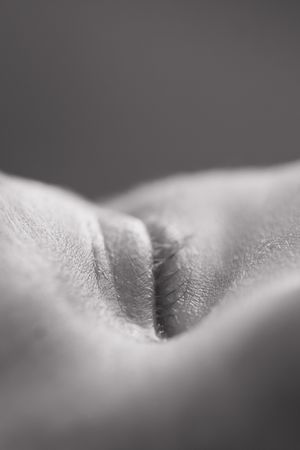 Close-up black and white macro photo of human skin texture showing a natural fold or crease in soft focus.