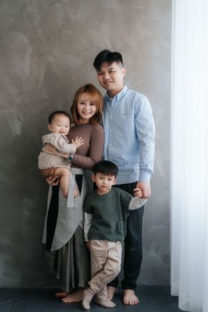 Family portrait session in a modern studio with grey walls and minimalist decor.在現代風格的攝影棚拍攝全家福，攝影棚的牆壁是灰色的，裝飾風格簡約。