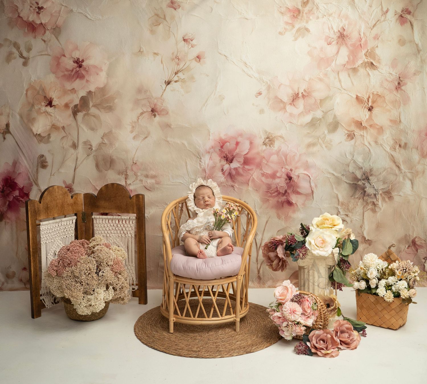 Newborn baby posed in wicker chair surrounded by pink floral backdrop at The Affinity Studio in St. Augustine.
