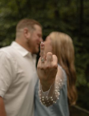 Engaged couple kissing while woman displays diamond engagement ring toward camera.