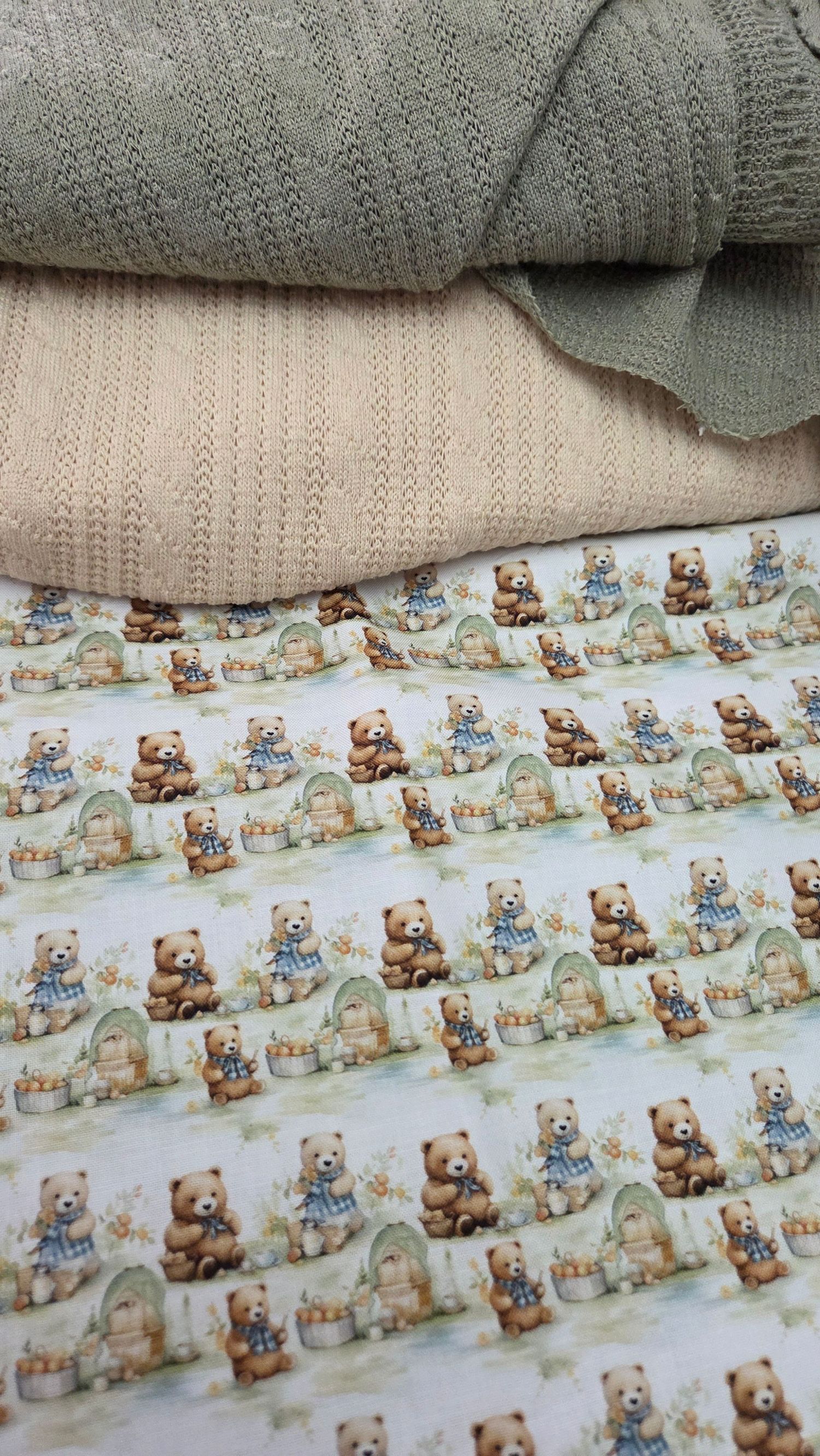 Stacked baby blankets with teddy bear print fabric and knitted throws in neutral tones.