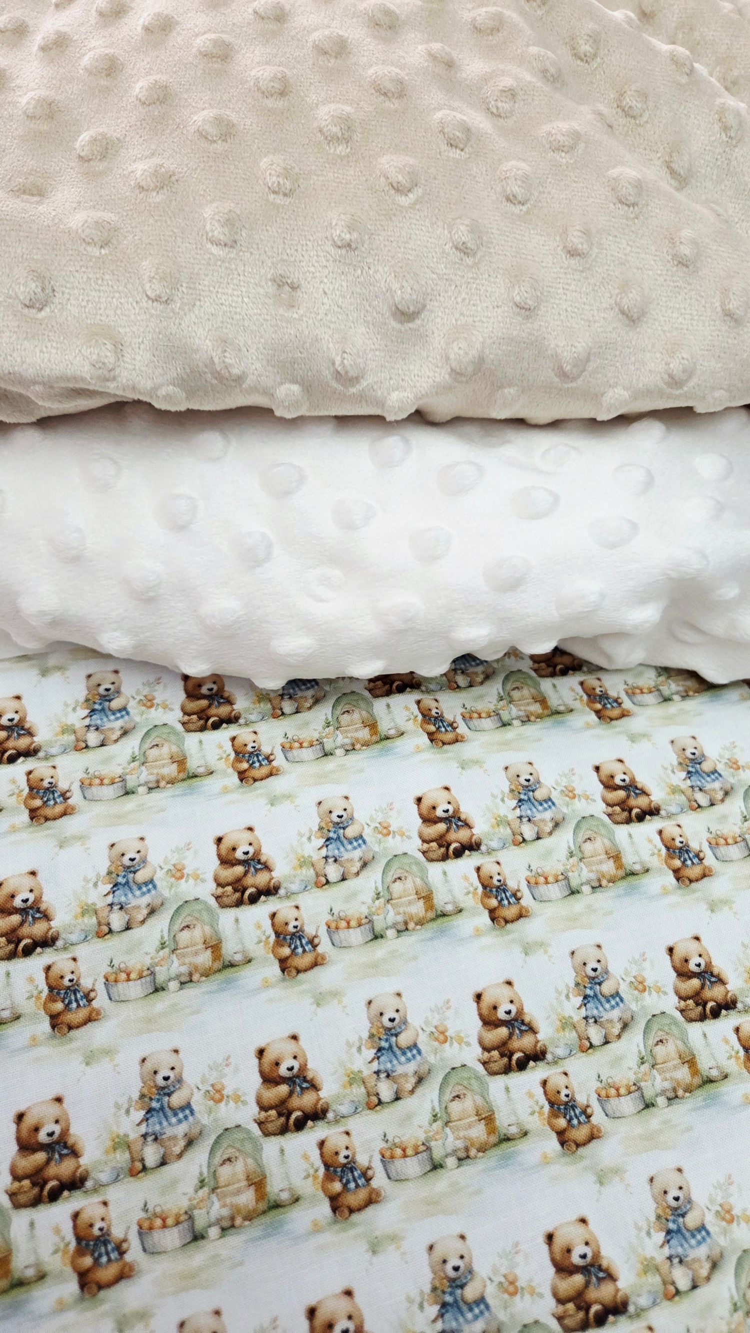 Stack of three fabric layers featuring cream minky dot fleece and white minky with teddy bear print baby fabric.