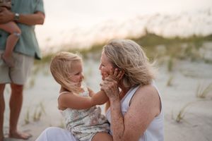 Grandmother and granddaughter sharing tender moment on beach at golden hour.