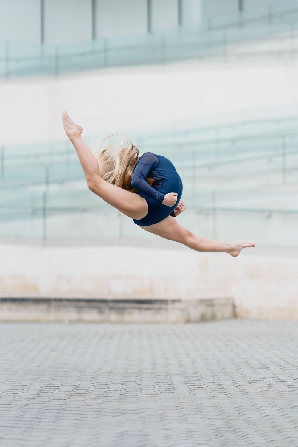 A dancer performs a graceful horizontal levitation pose against a light blue background.