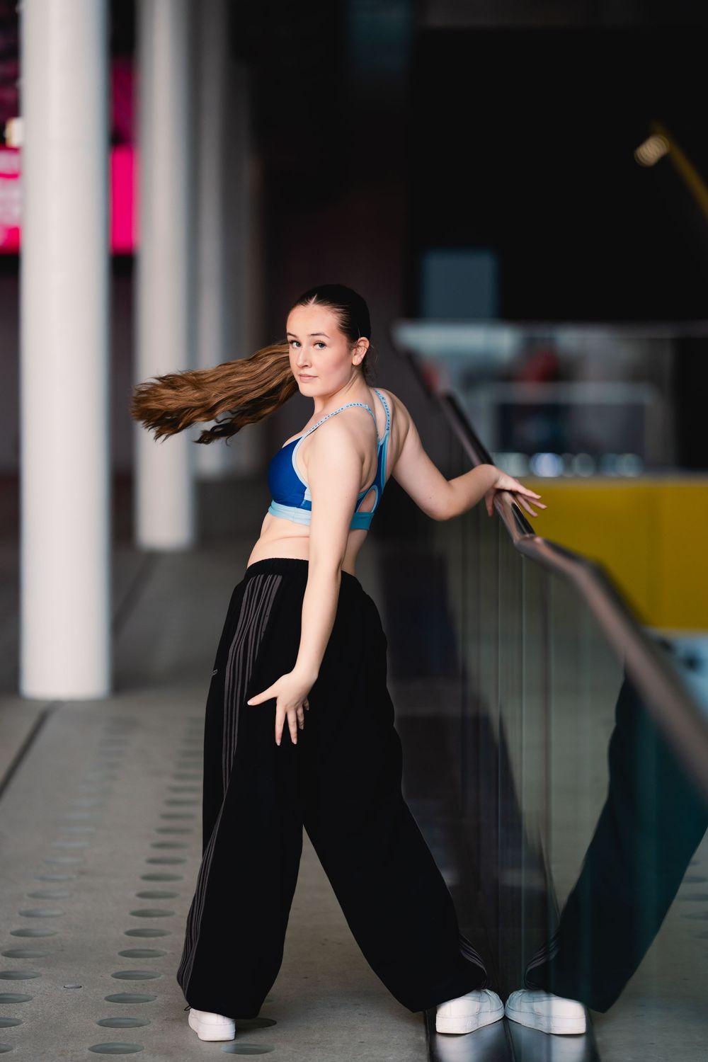 A dancer in a black outfit performs a graceful movement sequence while leaning against a wall.