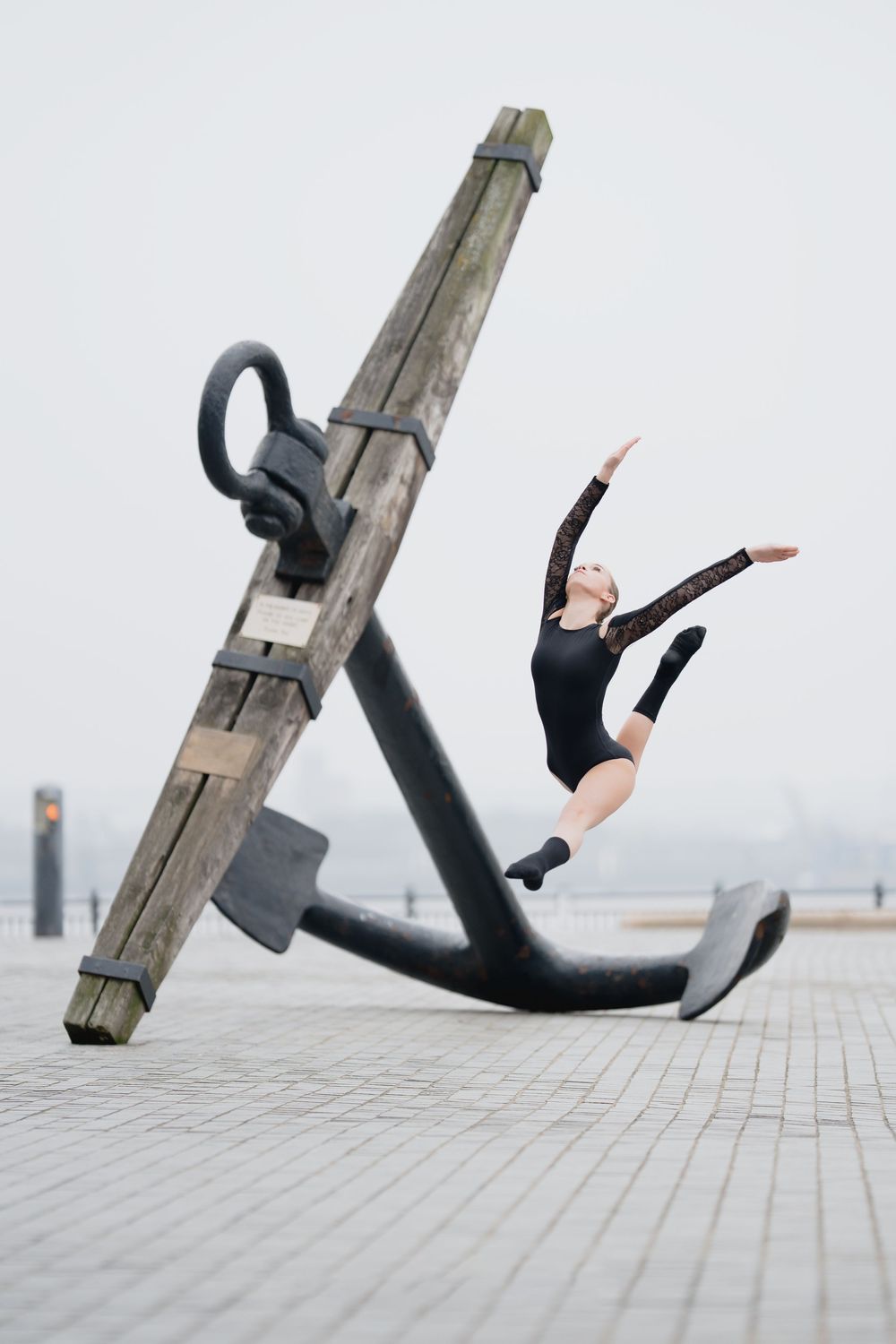 A sequence of artistic dance photos showing a person in black leotard interacting with a large anchor sculpture.