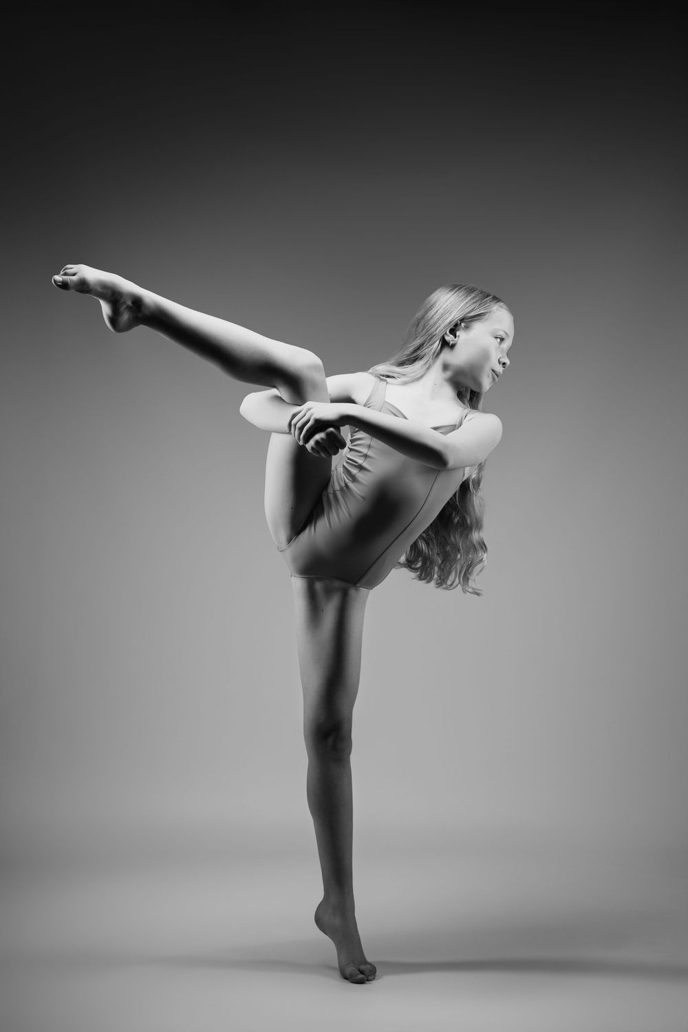 A contemporary dancer performs an elegant arabesque pose in black and white.