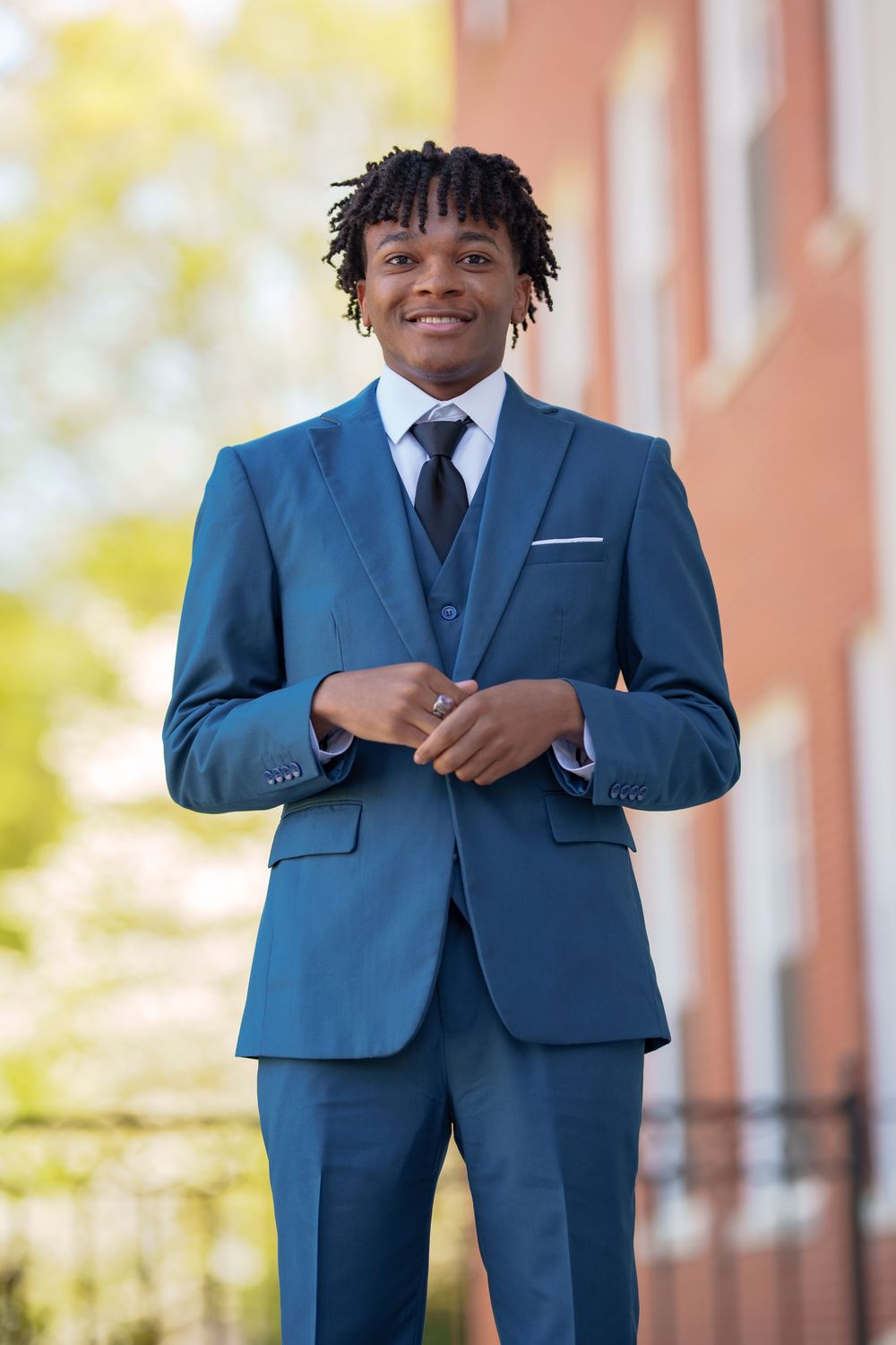 Professional wearing tailored blue three-piece suit standing outdoors.