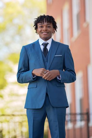 Professional wearing tailored blue three-piece suit standing outdoors.