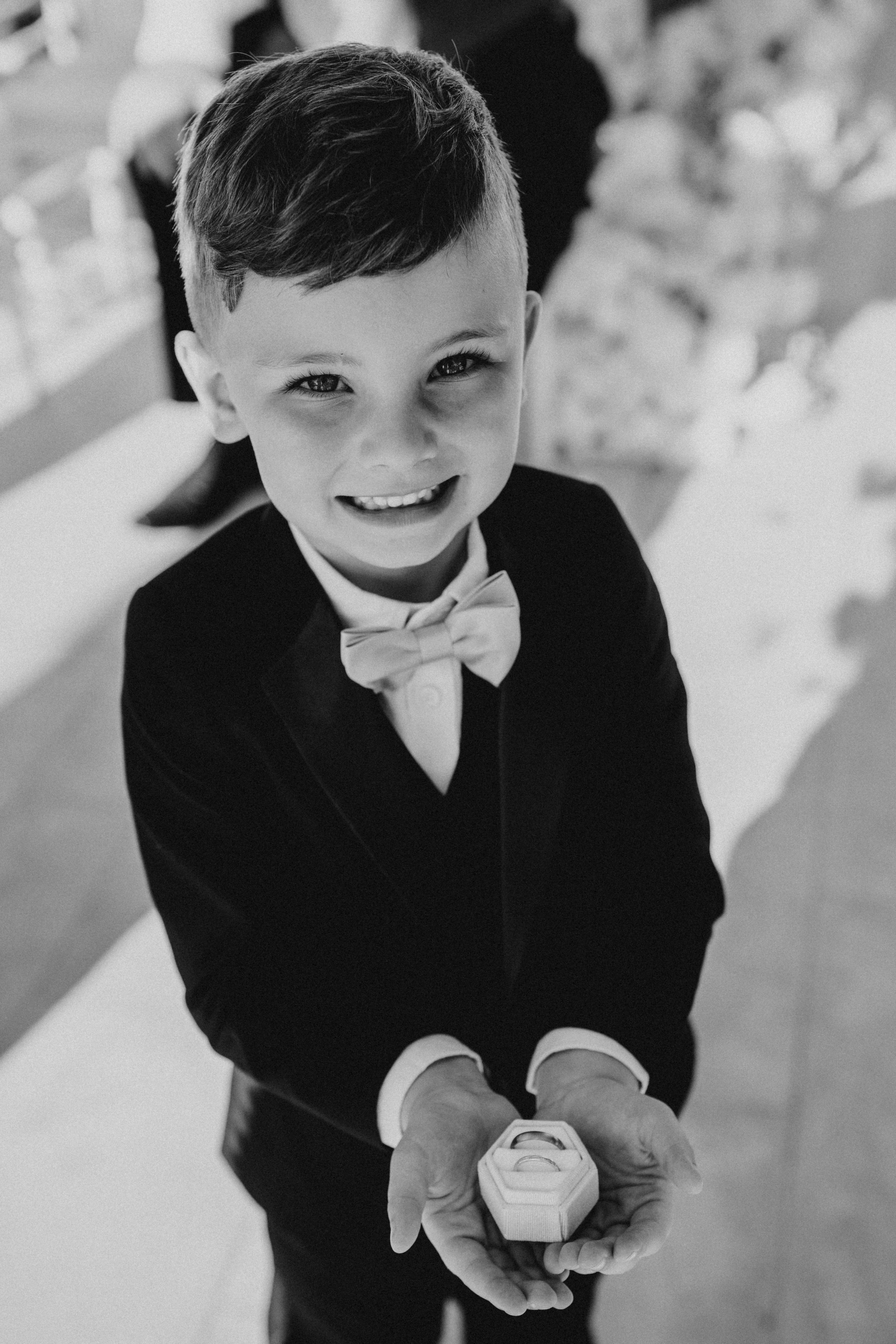 Black and white photo series of a young child in formal attire smiling and holding a small object.