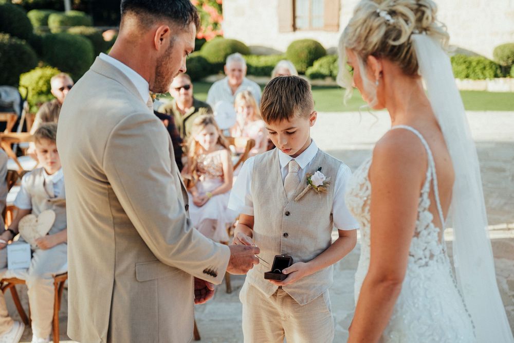 A group celebrates during an outdoor wedding ceremony with guests gathered around in a sunny garden setting.