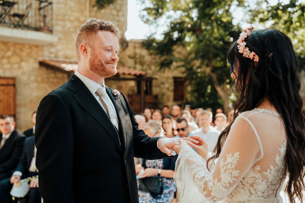 Newlyweds share their first dance surrounded by guests at an elegant stone venue with natural lighting.