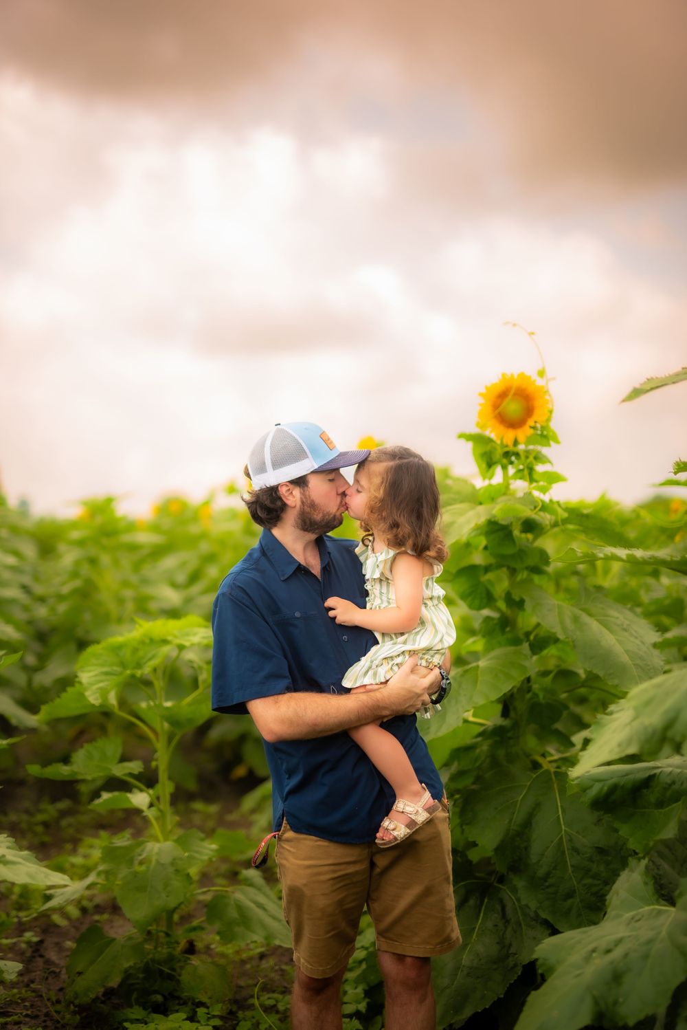 Tender moment between parent and child in sunflower field at sunset.