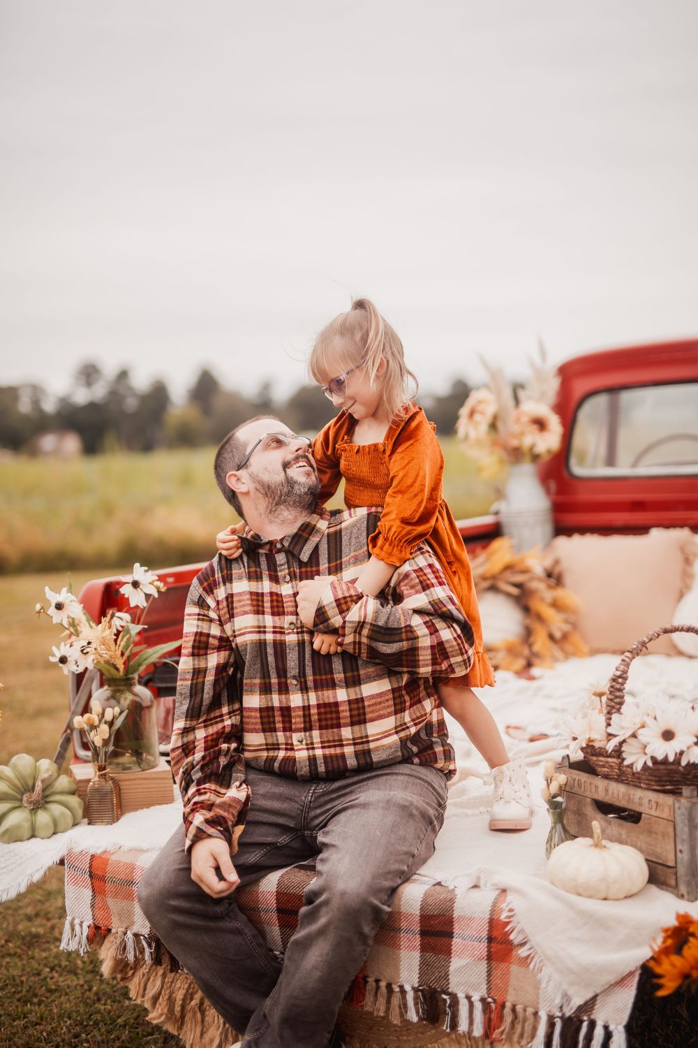 Autumn themed picnic setup with plaid blanket, vintage truck, and cozy outdoor decor with pumpkins and black cat ornaments.