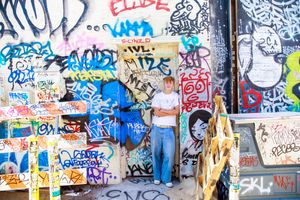 Urban wall covered in layers of graffiti tags and street art with overlapping text and designs in various colors.
