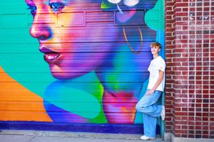 A bright turquoise wall features large-scale street art murals with bold gradient colors and geometric designs.