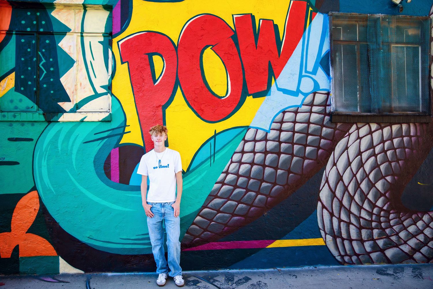 A colorful graffiti wall with large text and geometric patterns serves as a vibrant backdrop against a teal and yellow design.