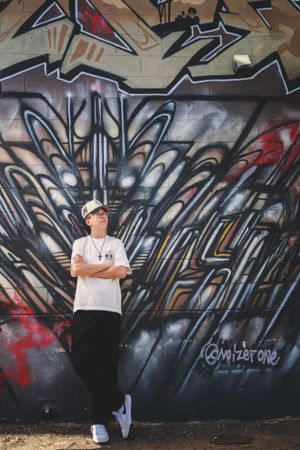 Urban portrait against graffiti wall featuring geometric black and grey designs.