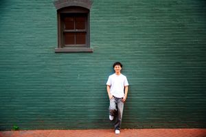 Person in white shirt poses against green wall in sequence of four similar photos.