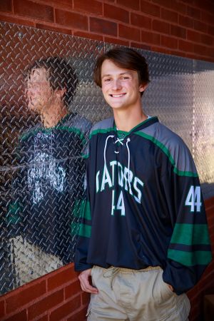 Student athlete wearing green and black Gators sports jersey posing against textured wall.
