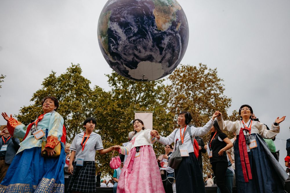 Group celebrating under large globe installation at cultural festival.