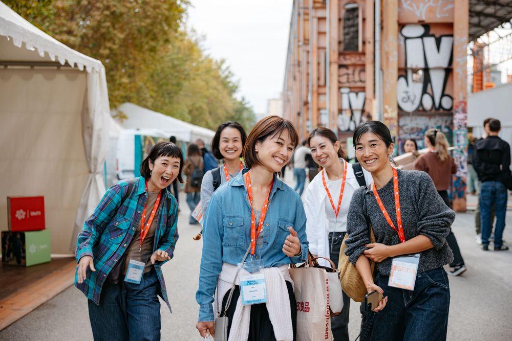 Group of friends with event badges walking together at an outdoor festival.