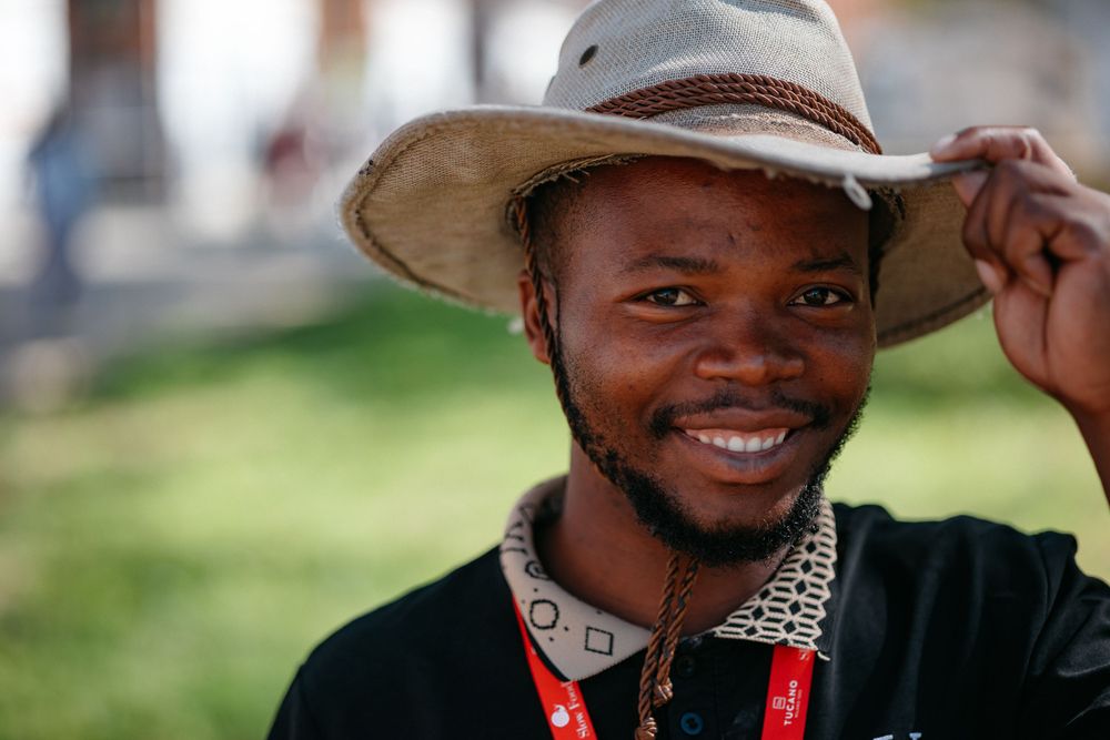Person wearing a wide-brimmed hat and patterned collar outdoors.
