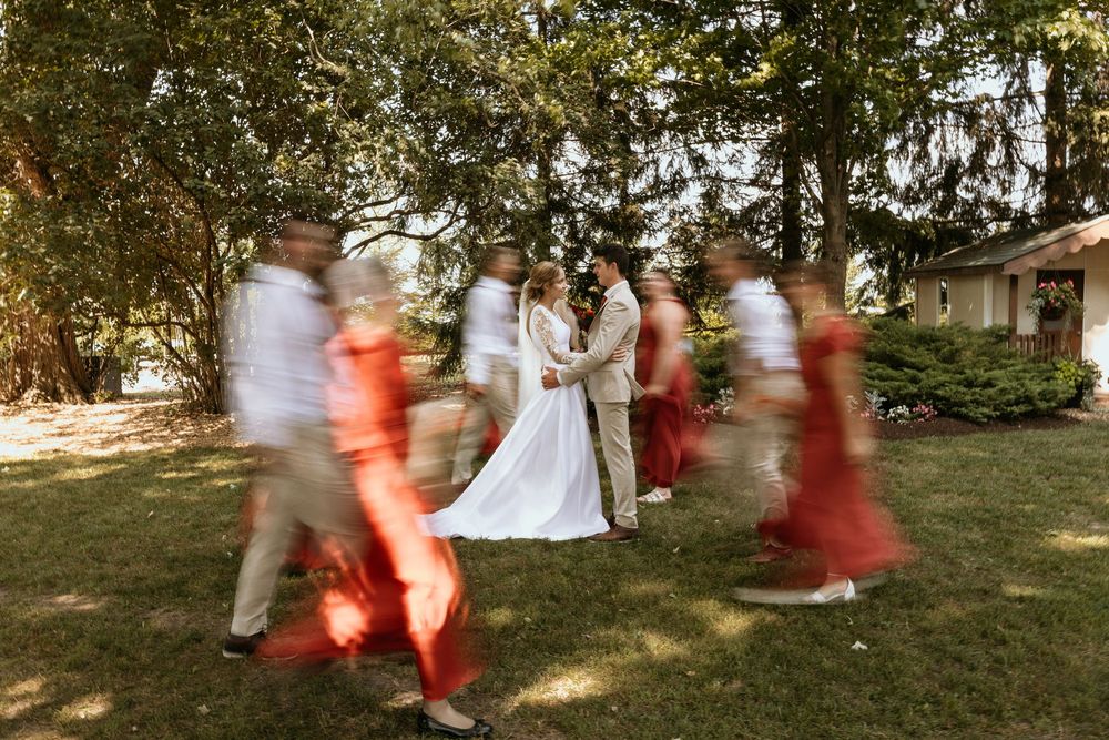 White-clad figures dance in a circular motion on grass, creating a dreamy motion blur effect in golden sunlight.