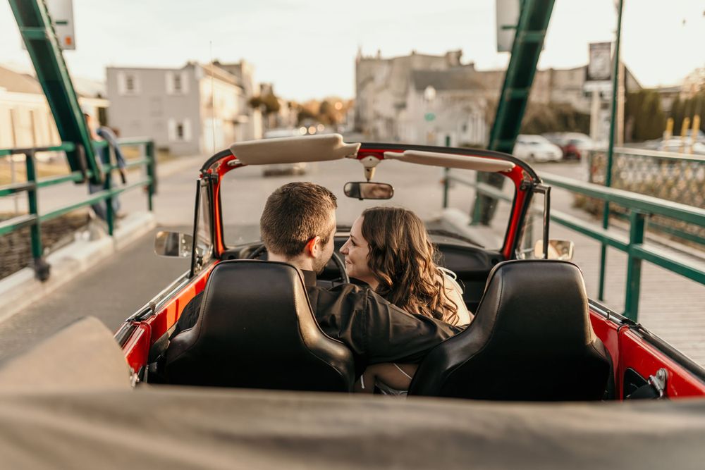 A couple sharing an intimate moment in a vintage convertible car on a city street.