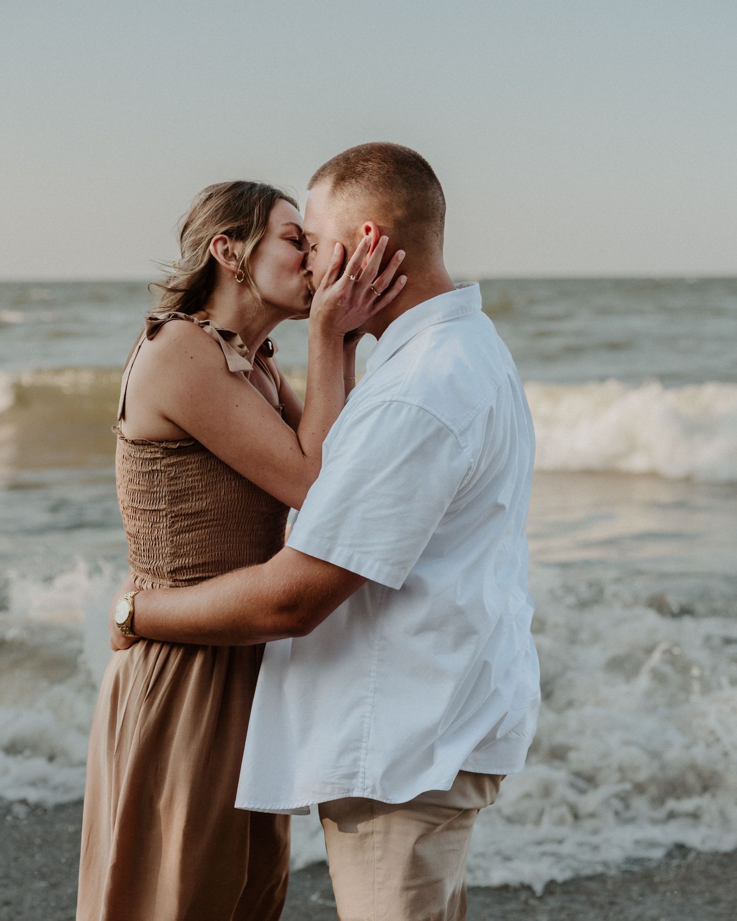 A tender romantic moment shared between a couple on a beach at dusk.