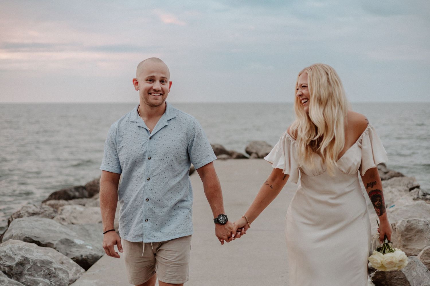 Happy couple shares a romantic moment on coastal rocks at dusk.