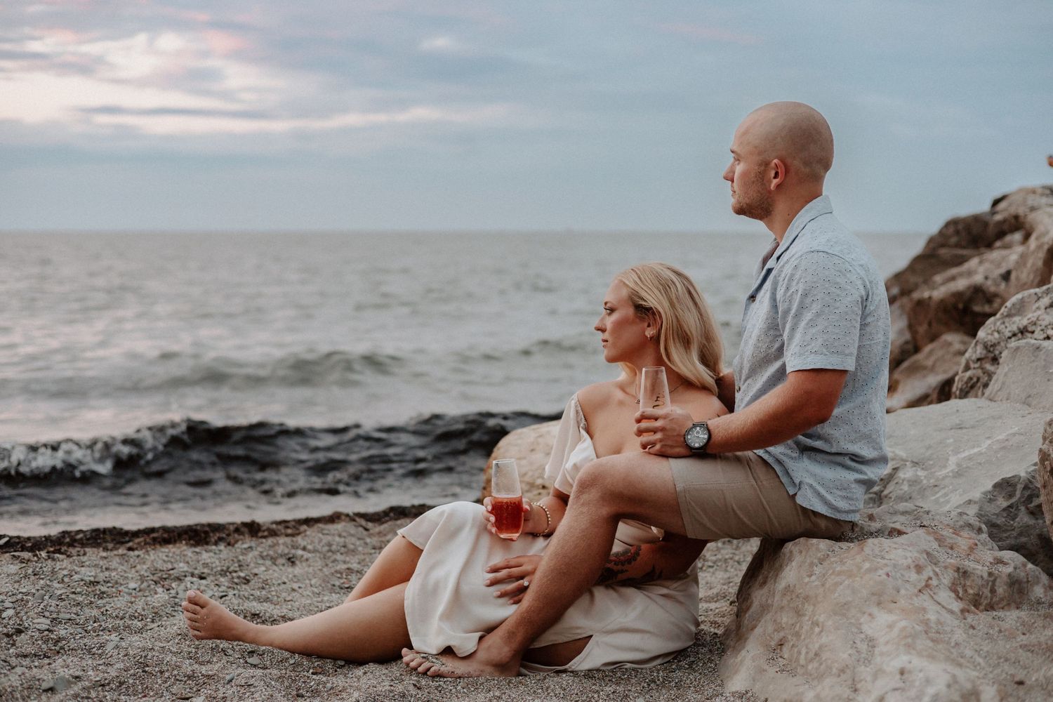 Couple enjoying intimate moment on rocky beach during sunset.