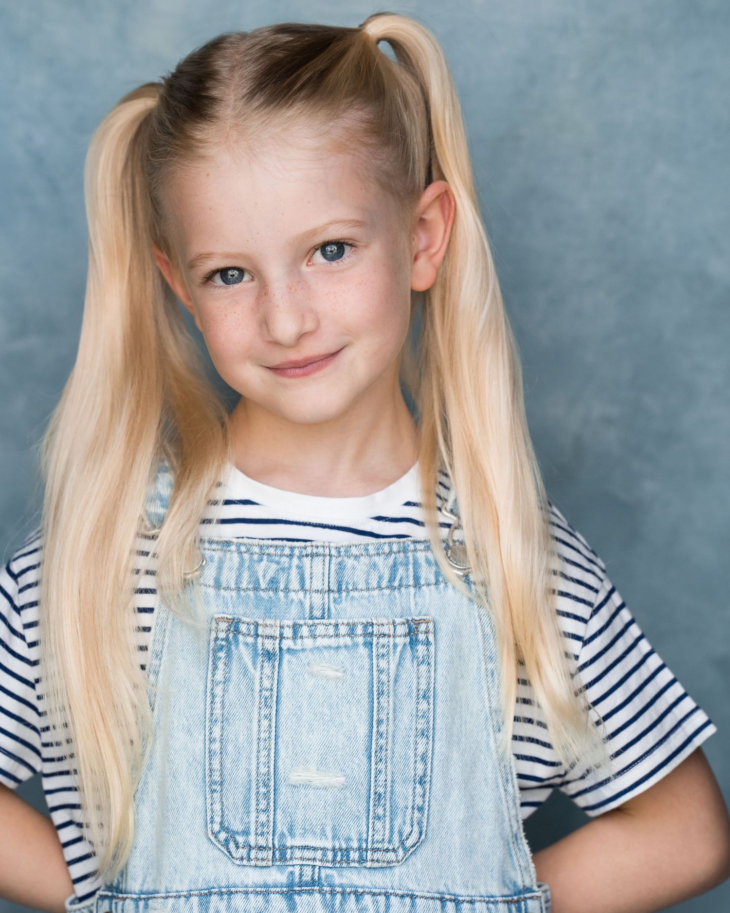 Studio portrait wearing blue floral pattern and white top against light background.