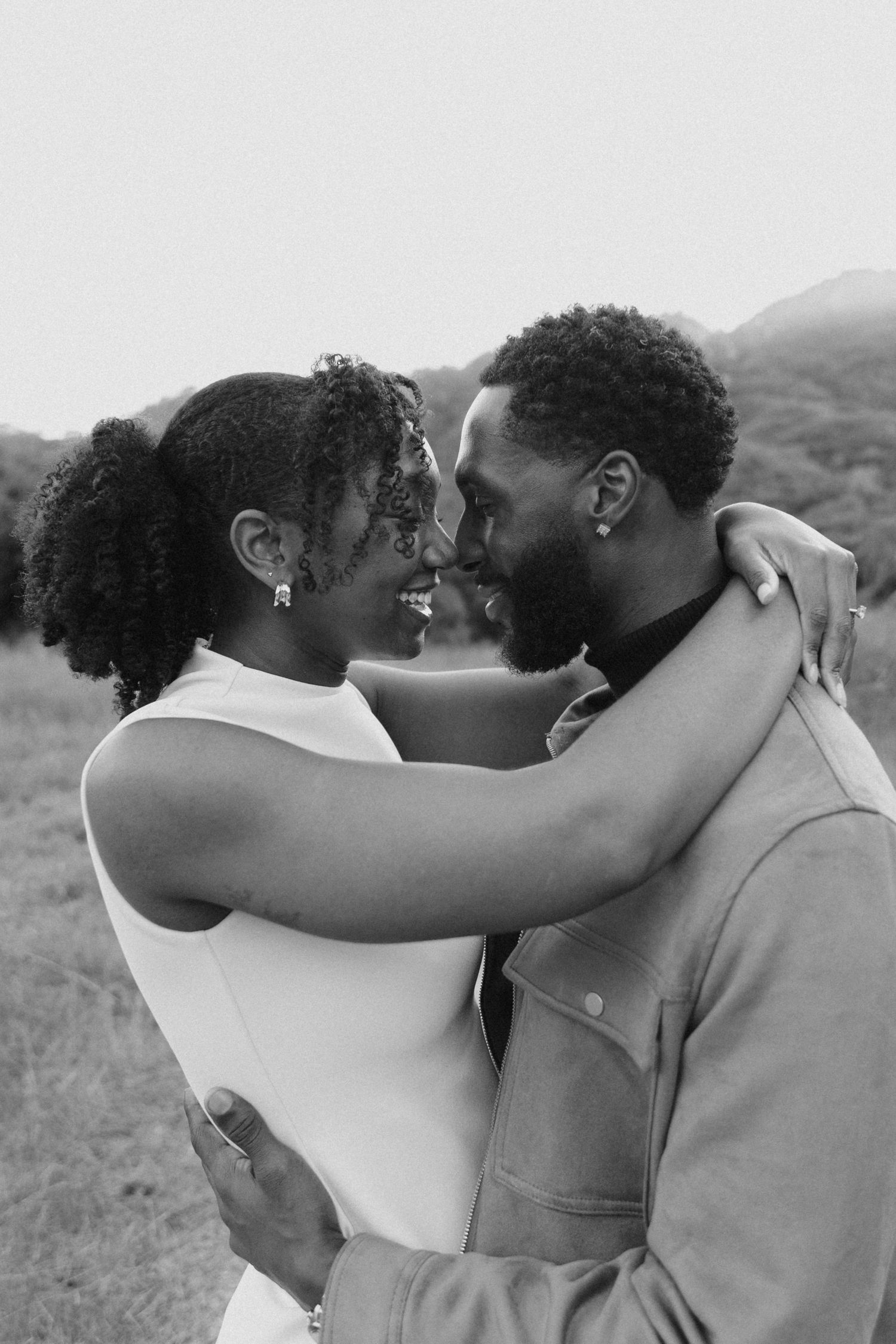 A sequence of black and white photographs showing two people embracing outdoors with mountains in the background.