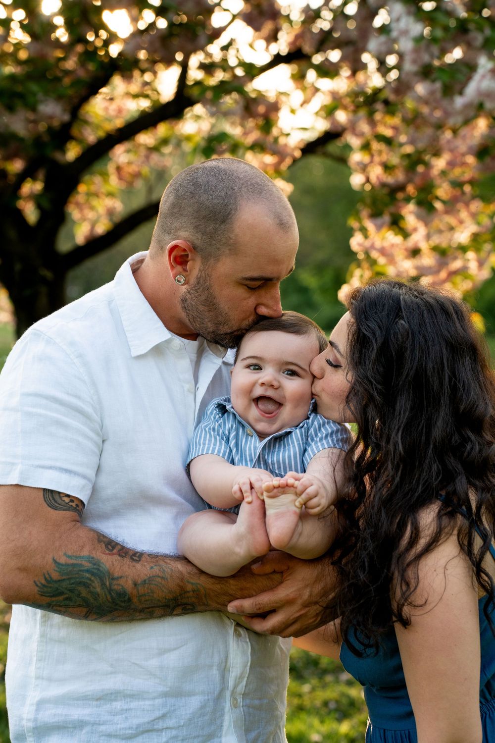 A joyful family moment captured outdoors during golden hour with blossoming trees in the background.