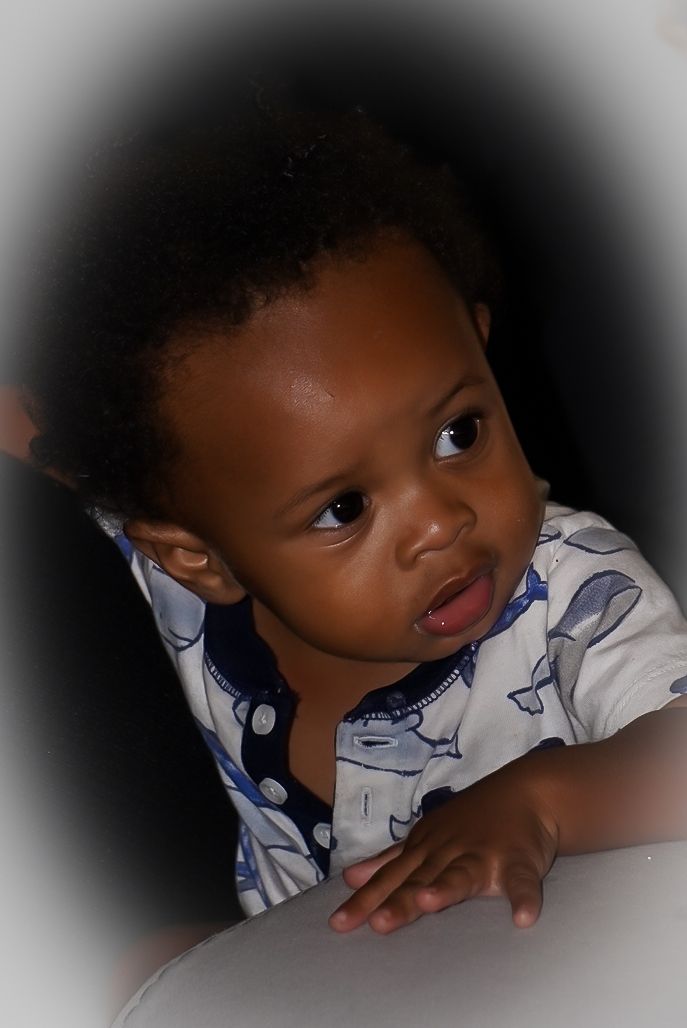 A young child in a white and blue patterned shirt looks up with a curious expression.