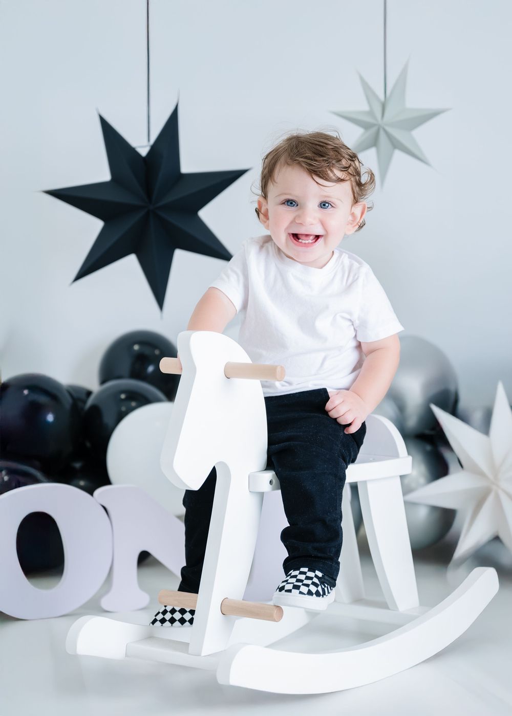 White rocking horse and decorative stars create a festive holiday photo setting with black and silver accents.