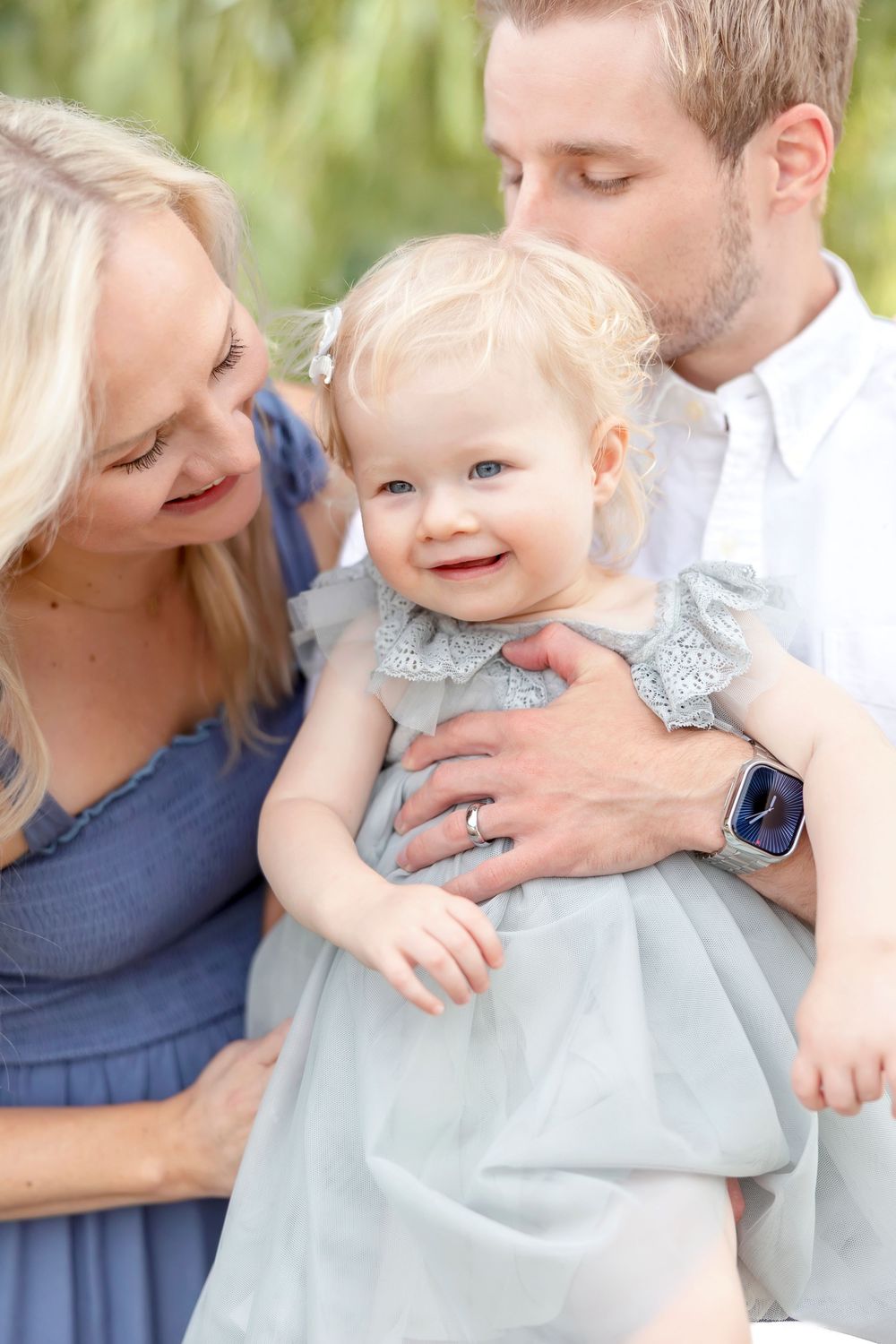 Sweet candid moments between parents and young child in coordinated blue outfits.