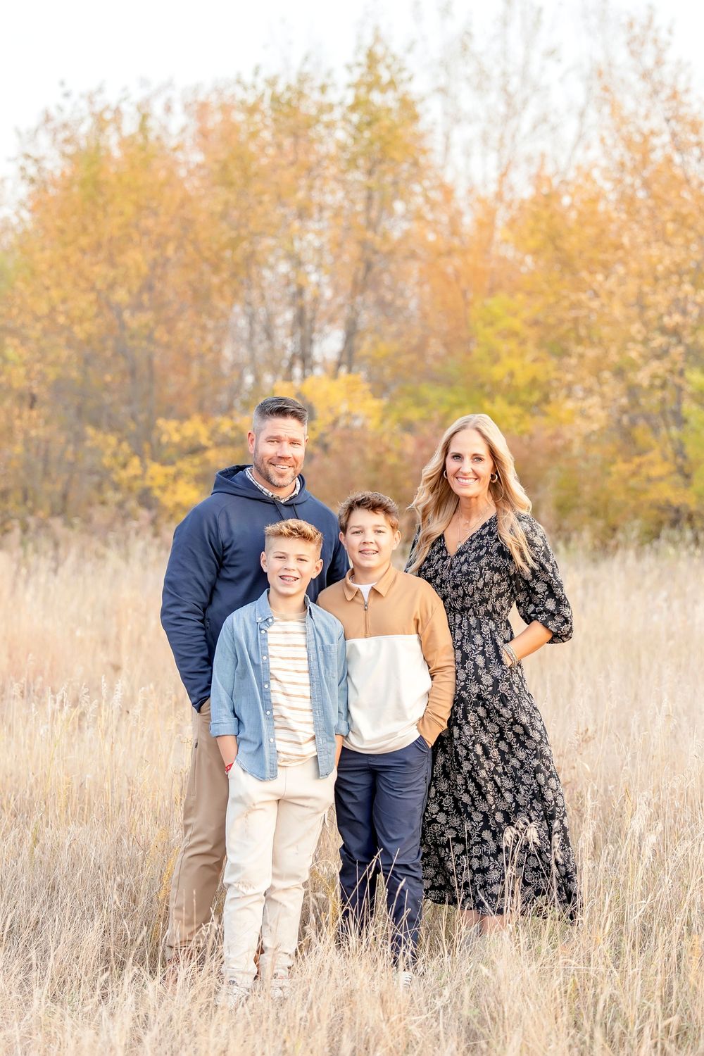 A family stands together in a field of tall grass during golden hour.