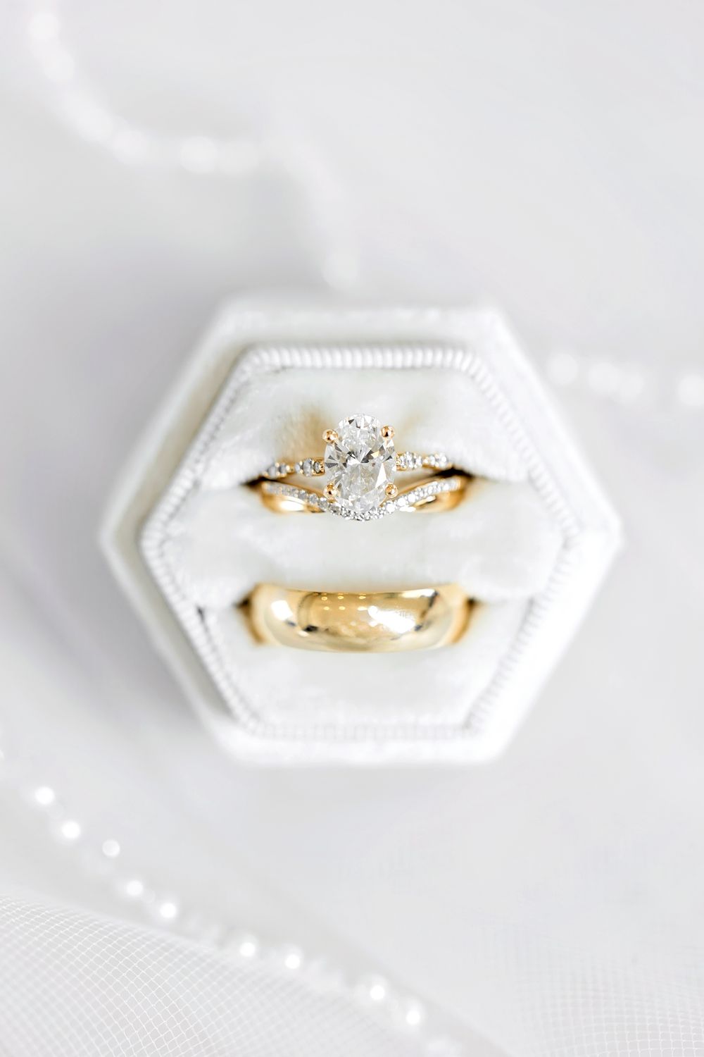 Delicate gold engagement ring with diamond details on a hexagonal white display. Editorial Wedding Photography