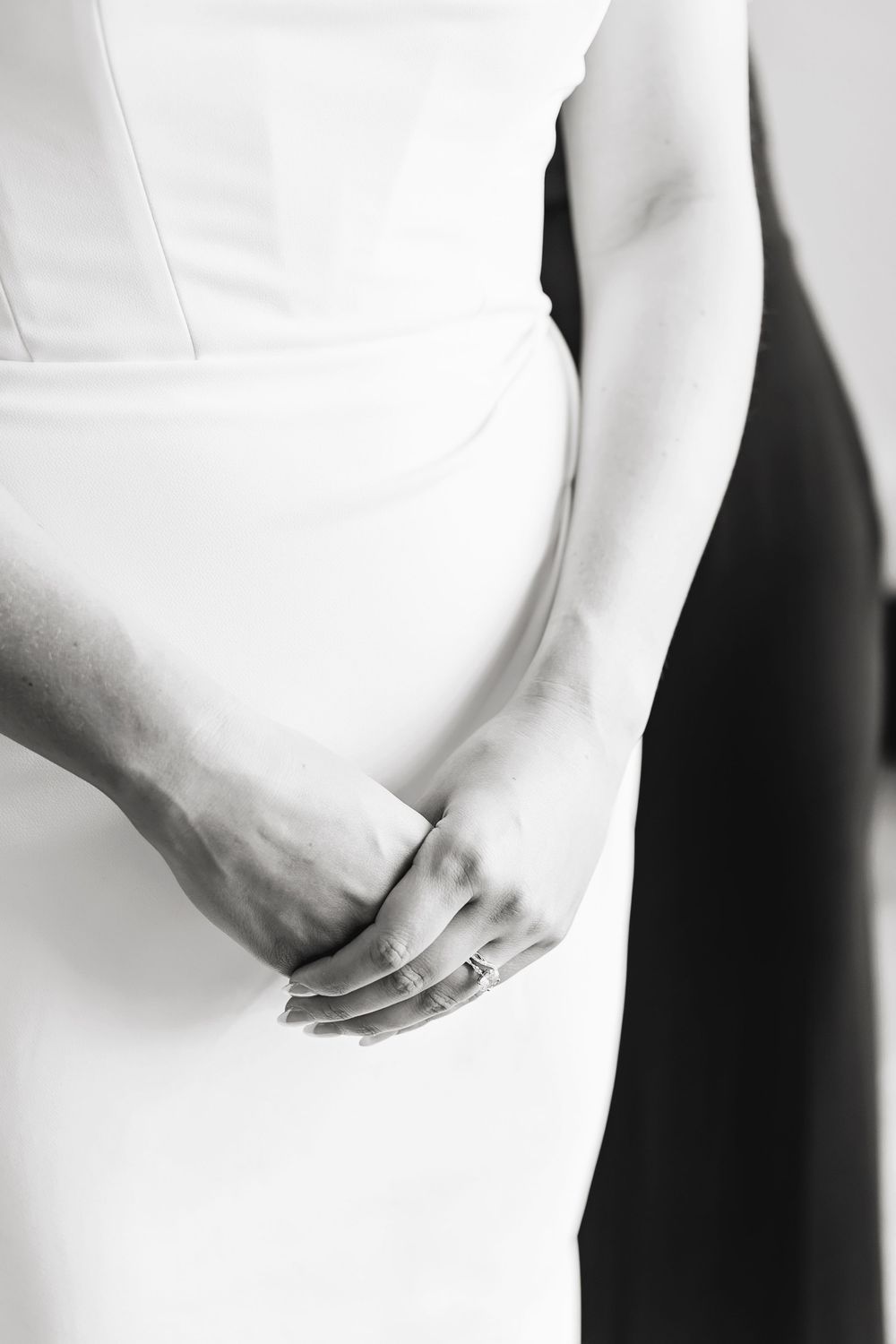 Close-up of hands in white sleeves against a dark background. Editorial Wedding Photography