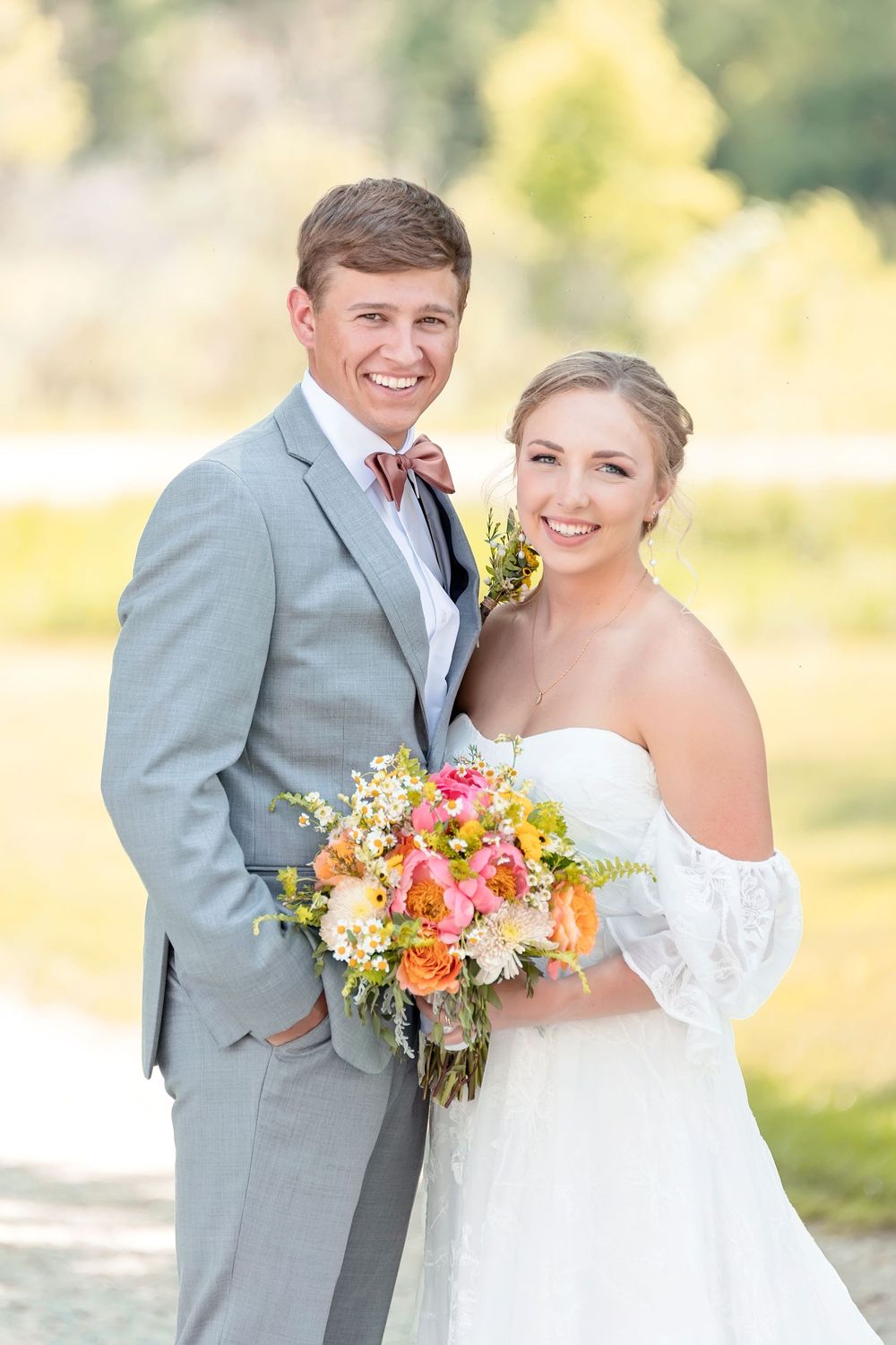 Summer wedding couple shares candid moments with bright floral bouquet in natural lighting.