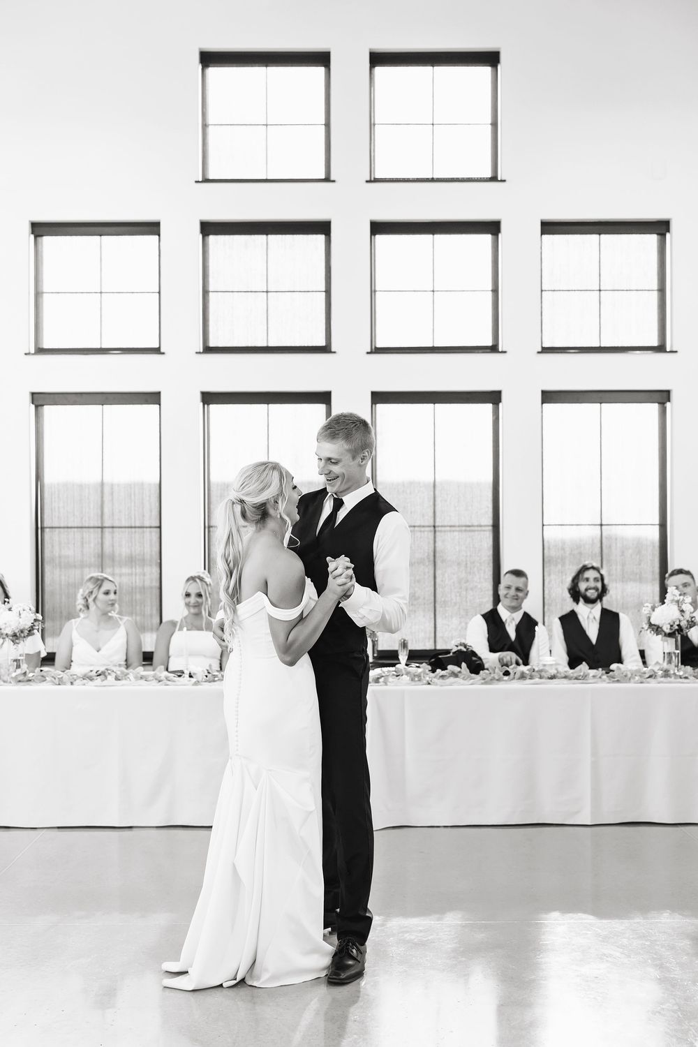 Black and white reception venue with elegant table settings and large windows.